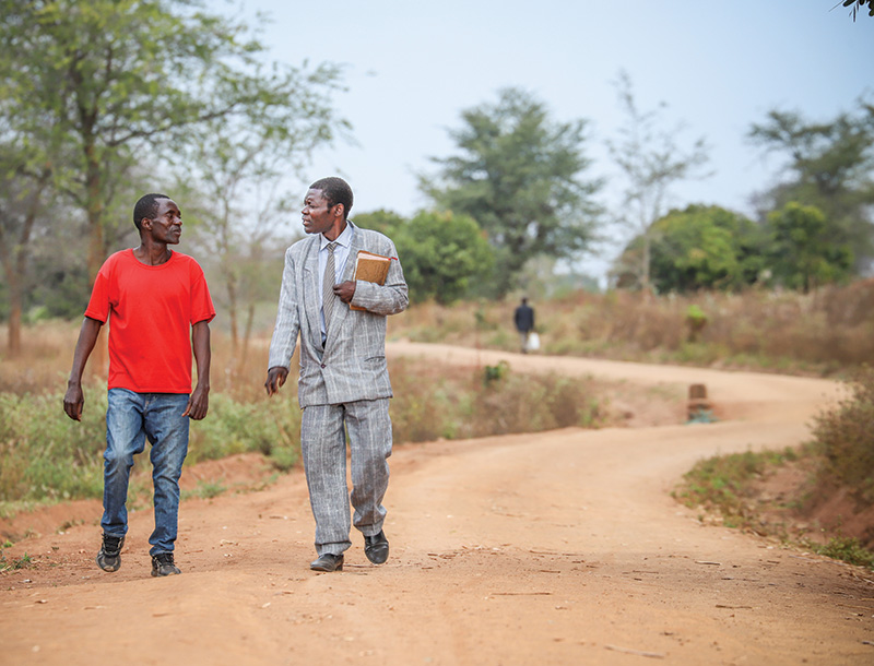 Two men walking down dirt road