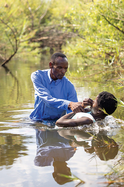 Man baptizing boy in river