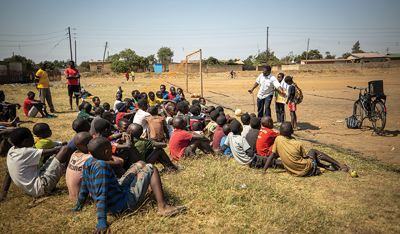 Preacher talking to group of kids on soccer field