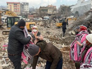 Volunteers handing out blankets to others in the midst of earthquake destruction.